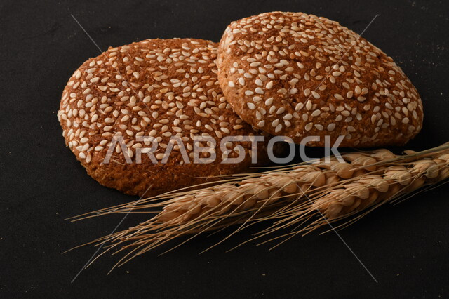 صورة مقربة لمجموعة من نباتات القمح ، وبسكويت القمح الهشة والمقرمشة على خلفية سوداء