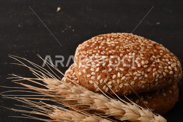 صورة مقربة لمجموعة من نباتات القمح ، وبسكويت القمح الهشة والمقرمشة على خلفية سوداء