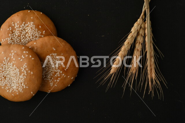 صورة مقربة لمجموعة من نباتات القمح ، وبسكويت القمح الهشة والمقرمشة على خلفية سوداء