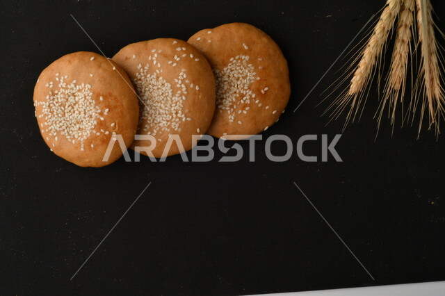 صورة مقربة لمجموعة من نباتات القمح ، وبسكويت القمح الهشة والمقرمشة على خلفية سوداء