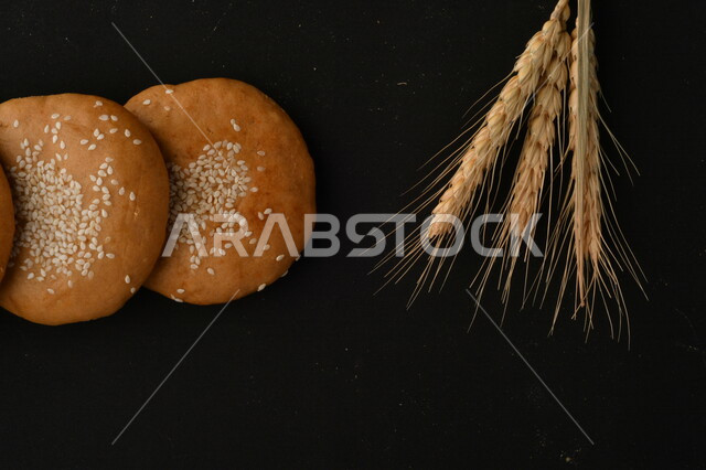 صورة مقربة لمجموعة من نباتات القمح ، وبسكويت القمح الهشة والمقرمشة على خلفية سوداء