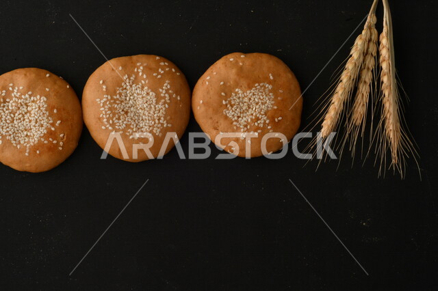 صورة مقربة لمجموعة من نباتات القمح ، وبسكويت القمح الهشة والمقرمشة على خلفية سوداء