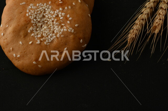 صورة مقربة لمجموعة من نباتات القمح ، وبسكويت القمح الهشة والمقرمشة على خلفية سوداء