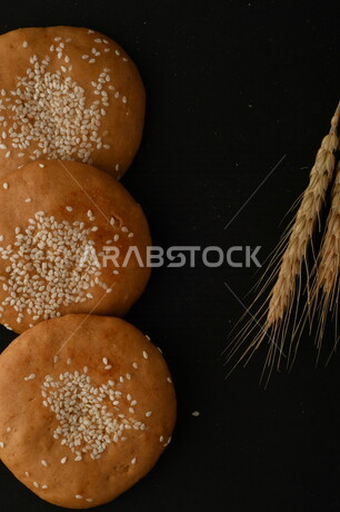 صورة مقربة لمجموعة من نباتات القمح ، وبسكويت القمح الهشة والمقرمشة على خلفية سوداء