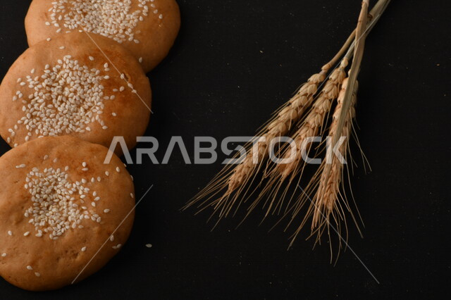 صورة مقربة لمجموعة من نباتات القمح ، وبسكويت القمح الهشة والمقرمشة على خلفية سوداء