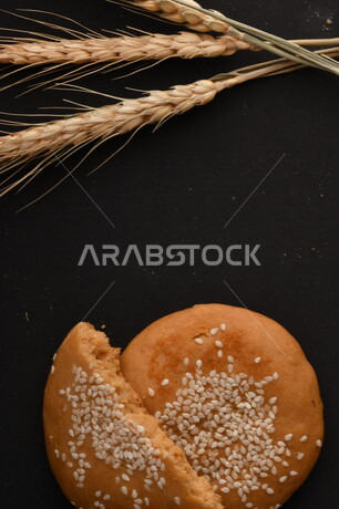 صورة مقربة لمجموعة من نباتات القمح ، وبسكويت القمح الهشة والمقرمشة على خلفية سوداء