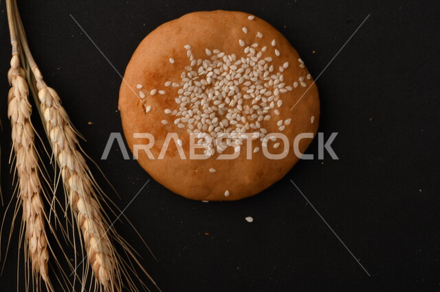 صورة مقربة لمجموعة من نباتات القمح ، وبسكويت القمح الهشة والمقرمشة على خلفية سوداء