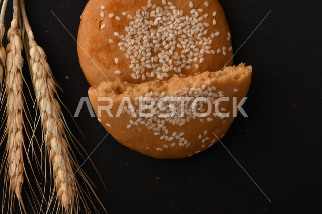 صورة مقربة لمجموعة من نباتات القمح ، وبسكويت القمح الهشة والمقرمشة على خلفية سوداء