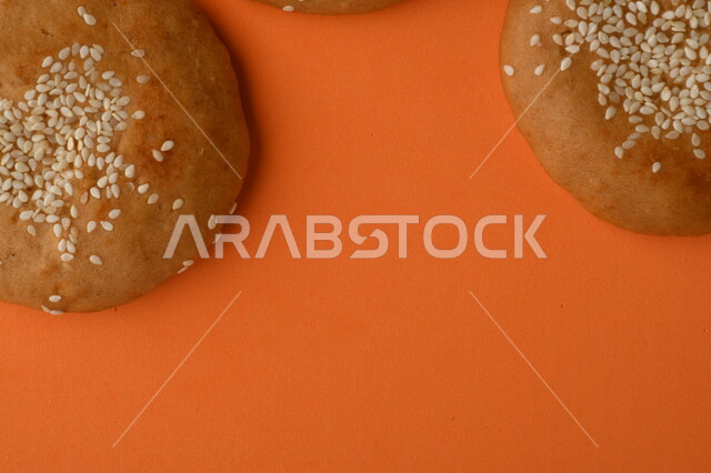 صورة مقربة لمجموعة من نباتات القمح ، وبسكويت القمح الهشة والمقرمشة على خلفية برتقالية اللون