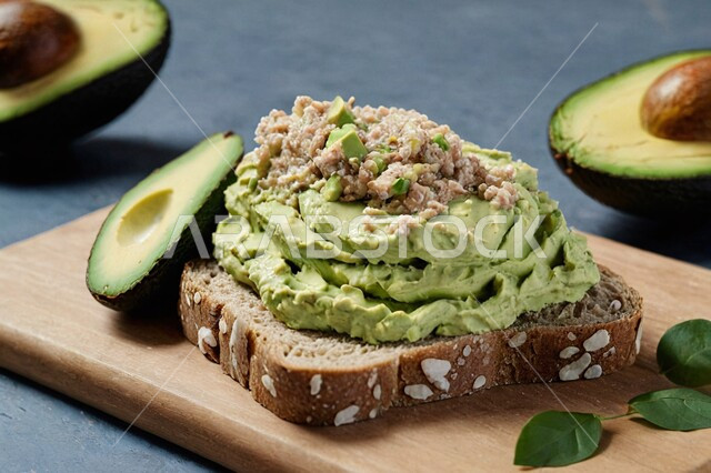 وجبات مفيدة لإتباع نظام غذائي صحي، قطعة من التوست وشرائح الأفوكادو الطازجة والصحية على لوح خشبي، وجبة الفطور ذات قيمة غذائية عالية، وصفات وأطباق الطعام اللذيذة