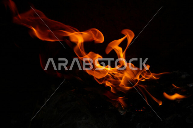 لهب النار على خلفية سوداء من الفن التجريدي ،  الشرارات الساخنة المحترقة ، صورة للنار المتوهجة برتقالية اللون