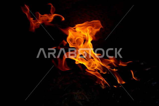 لهب النار على خلفية سوداء من الفن التجريدي ،  الشرارات الساخنة المحترقة ، صورة للنار المتوهجة برتقالية اللون