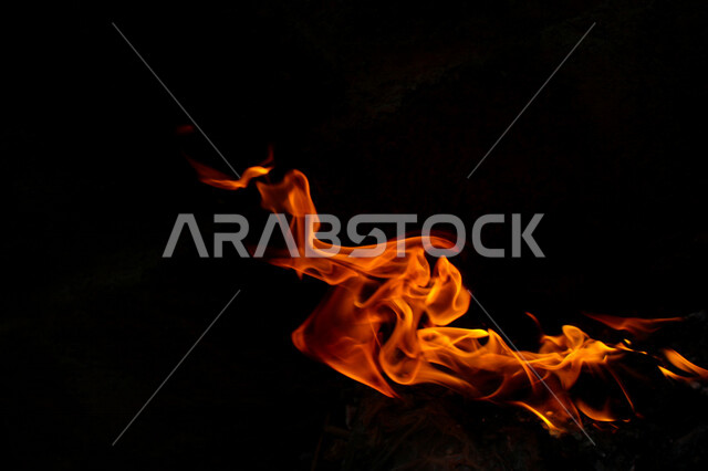 لهب النار على خلفية سوداء من الفن التجريدي ،  الشرارات الساخنة المحترقة ، صورة للنار المتوهجة برتقالية اللون