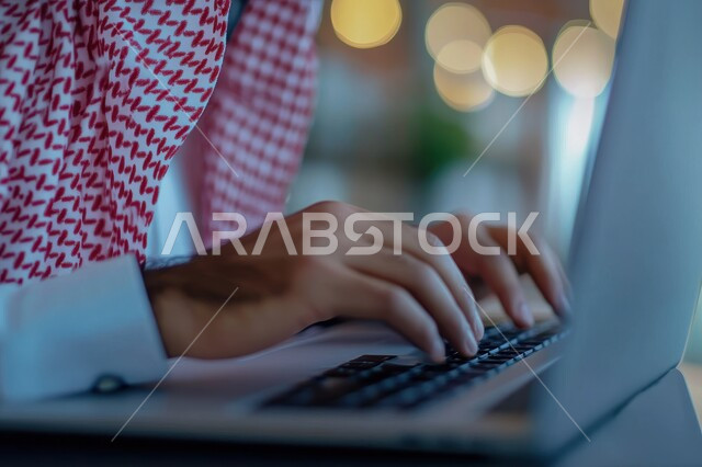 إدارة شؤون الأعمال وتنظيمها عبر الاجهزة التقنية، مهن ووظائف ادارية مكتبية، دمج العمل مع التكنولوجيا، صورة مقربة من الجانب لرجل اعمال عربي خليجي سعودي يرتدي الزي التقليدي والشماغ يعمل على الحاسوب المحمول