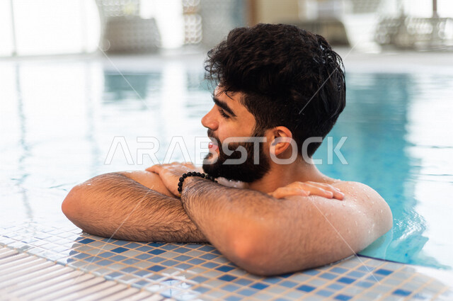 A young Arab from the Saudi, the fun of swimming, training in swimming, sitting and relaxing in the pool