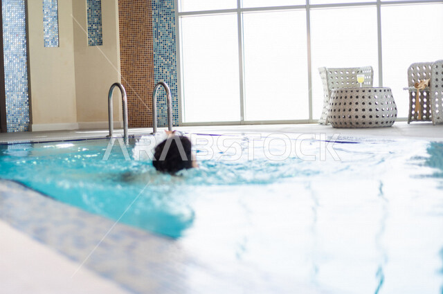 شاب عربي سعودي، متعة السباحة، التدرب على السباحة، الجلوس والاسترخاء في المسبح