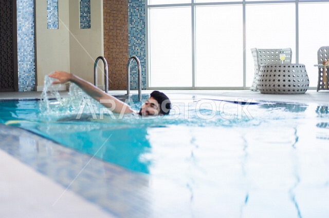 شاب عربي سعودي، متعة السباحة، التدرب على السباحة، الجلوس والاسترخاء في المسبح