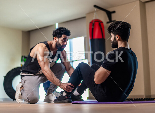 شاب عربي سعودي، يرتدي ملابس رياضية، اجراء تمارين ابراز عضلات البطن، صالة الألعاب الرياضية، ممارسة الرياضة، اللياقة البدنية