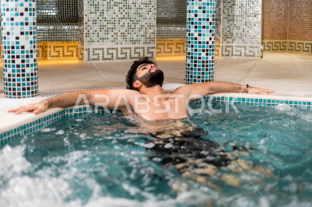 شاب عربي سعودي، الجلوس والاسترخاء في الجاكوزي، الاستمتاع بالماء الساخن، استخدام الماء الحار في المعالجة الجسدية