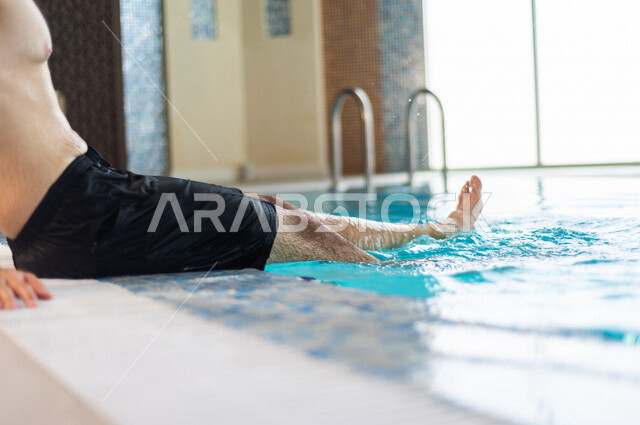 A young Arab from the Saudi, the fun of swimming, training in swimming, sitting and relaxing in the pool