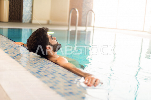 شاب عربي سعودي، متعة السباحة، التدرب على السباحة، الجلوس والاسترخاء في المسبح