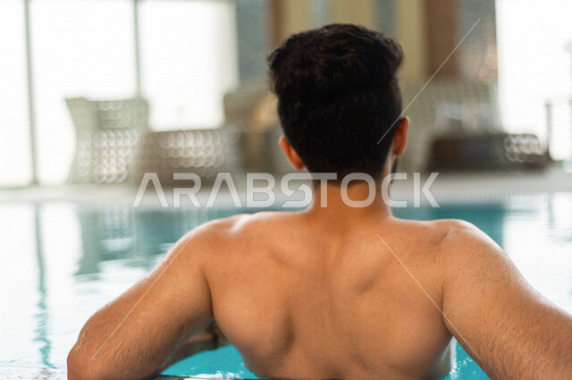 شاب عربي سعودي، متعة السباحة، التدرب على السباحة، الجلوس والاسترخاء في المسبح