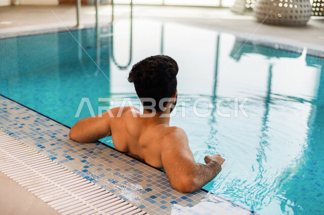 شاب عربي سعودي، متعة السباحة، التدرب على السباحة، الجلوس والاسترخاء في المسبح