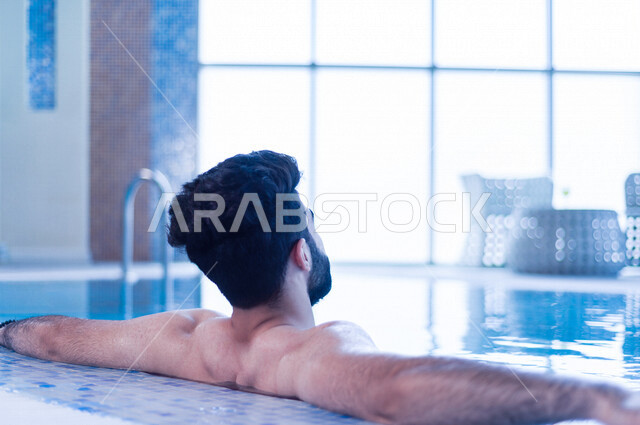 شاب عربي سعودي، متعة السباحة، التدرب على السباحة، الجلوس والاسترخاء في المسبح