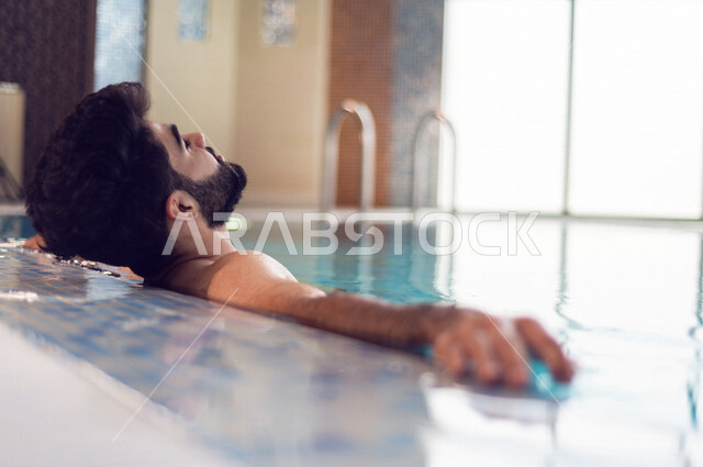A young Arab from the Saudi, the fun of swimming, training in swimming, sitting and relaxing in the pool