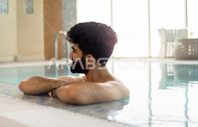 شاب عربي سعودي، متعة السباحة، التدرب على السباحة، الجلوس والاسترخاء في المسبح
