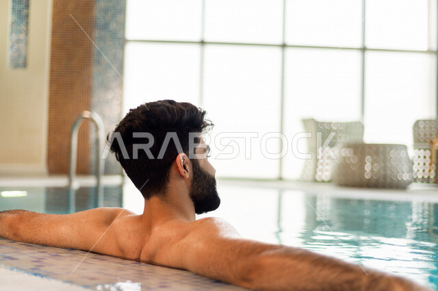 A young Arab from the Saudi, the fun of swimming, training in swimming, sitting and relaxing in the pool