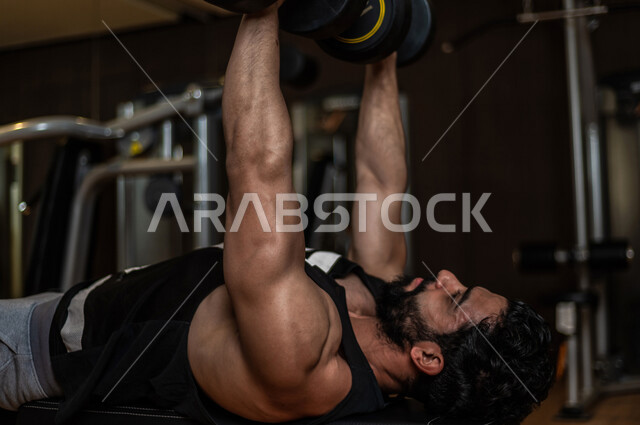 شاب عربي سعودي، التمرن في صالة كمال الاجسام، رفع الأثقال، كمال الأجسام، ممارسة الرياضة، اللياقة البدنية