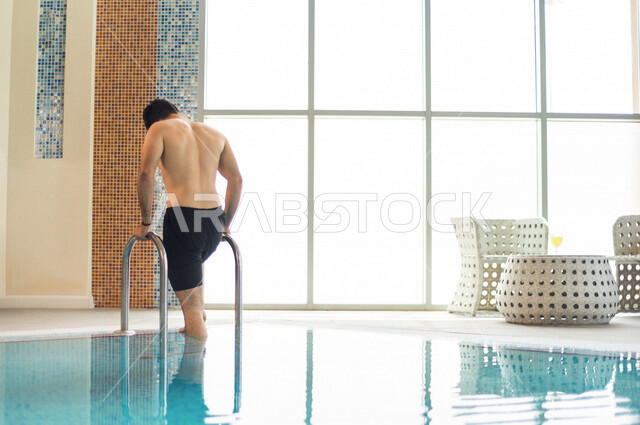 شاب عربي سعودي، متعة السباحة، التدرب على السباحة، الجلوس والاسترخاء في المسبح