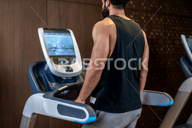 شاب عربي سعودي، يرتدي ملابس رياضية، التمرن والاحماء على جهاز المشي، صالة الألعاب الرياضية، تمارين قلب مكثفة، ممارسة الرياضة، اللياقة البدنية