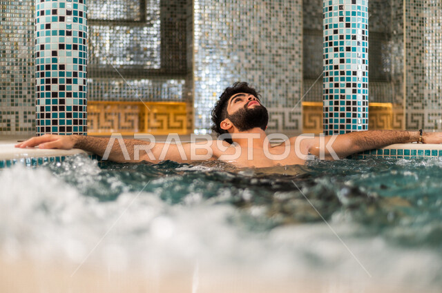 شاب عربي سعودي، الجلوس والاسترخاء في الجاكوزي، الاستمتاع بالماء الساخن، استخدام الماء الحار في المعالجة الجسدية