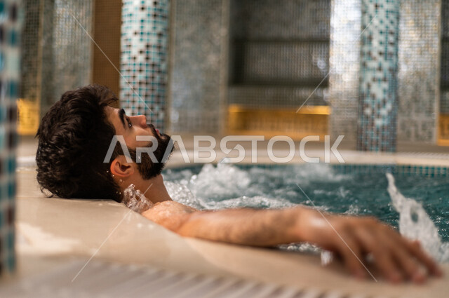 شاب عربي سعودي، الجلوس والاسترخاء في الجاكوزي، الاستمتاع بالماء الساخن، استخدام الماء الحار في المعالجة الجسدية