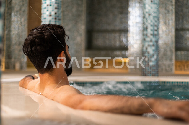 شاب عربي سعودي، الجلوس والاسترخاء في الجاكوزي، الاستمتاع بالماء الساخن، استخدام الماء الحار في المعالجة الجسدية