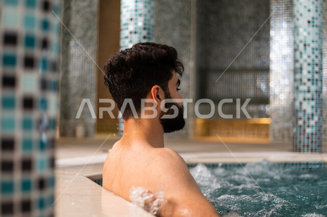شاب عربي سعودي، الجلوس والاسترخاء في الجاكوزي، الاستمتاع بالماء الساخن، استخدام الماء الحار في المعالجة الجسدية