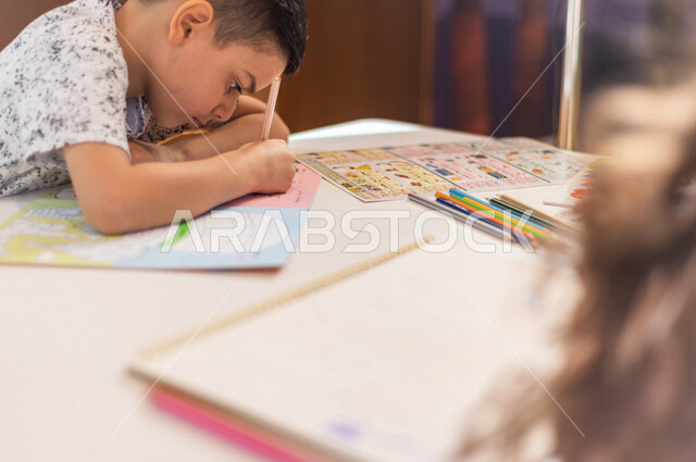 صورة مقربة لطفل عربي خليجي سعودي يبدع بنشاط تلوين الصور ، تعليم و ابداع ، تنمية المهارات ، حضانة أطفال ، روضة أطفال .