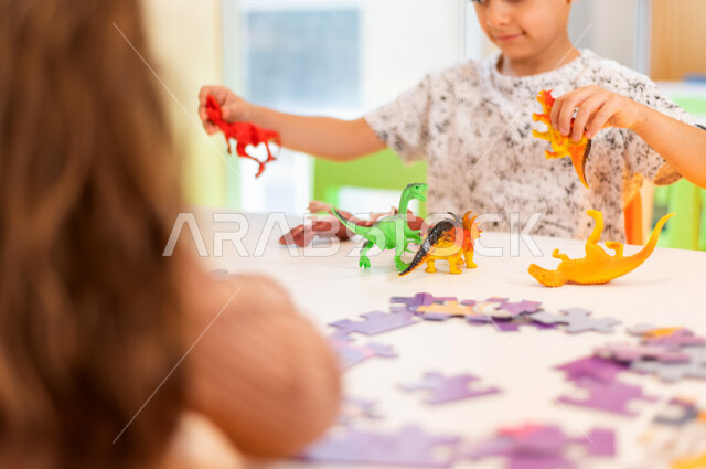 صورة مقربة لطفل عربي خليجي سعودي يلعب بألعاب الديناصورات ، ألعاب ترفيهية ، تعليم و ابداع ، تنمية المهارات ، حضانة أطفال ، روضة أطفال .