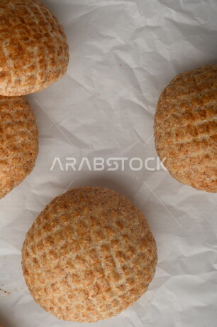 بسكوت المعمول الشعبية الهشة اللذيذة على ورق زبدة ، صورة لكعك بعجوة ويعرف بإسم كعك العيد الشهي ، خلفية بيضاء لحلويات شعبية طازجة