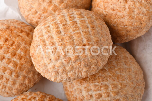 بسكوت المعمول الشعبية الهشة اللذيذة على ورق زبدة ، صورة لكعك بعجوة ويعرف بإسم كعك العيد الشهي ، خلفية بيضاء لحلويات شعبية طازجة