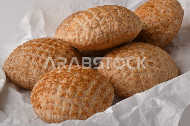 بسكوت المعمول الشعبية الهشة اللذيذة على ورق زبدة ، صورة لكعك بعجوة ويعرف بإسم كعك العيد الشهي ، خلفية بيضاء لحلويات شعبية طازجة