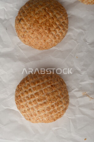 بسكوت المعمول الشعبية الهشة اللذيذة على ورق زبدة ، صورة لكعك بعجوة ويعرف بإسم كعك العيد الشهي ، خلفية بيضاء لحلويات شعبية طازجة