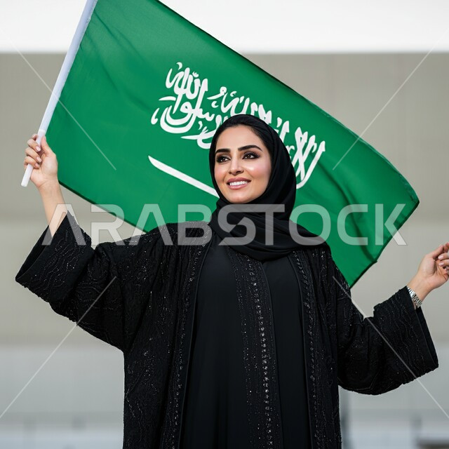 التعبير عن الفخر والاعتزاز بالانتماء للمملكة, ذكرى العيد الوطني السعودي 23 سبتمبر, صورة مقربة لامرأة عربية سعودية خليجية محجبة ترتدي العباءة السوداء تحمل بيدها علم السعودية للاحتفال بيوم العلم 11مارس