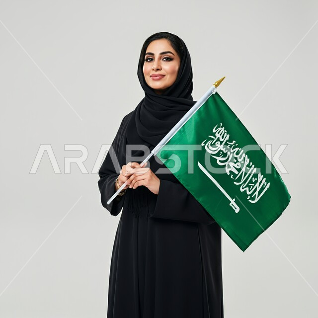 ذكرى العيد الوطني السعودي 23 سبتمبر, بورتريه لامرأة عربية سعودية خليجية محجبة ترتدي العباءة السوداء تحمل بيدها علم السعودية للاحتفال بيوم العلم 11مارس, التعبير عن الفخر والاعتزاز بالانتماء للمملكة