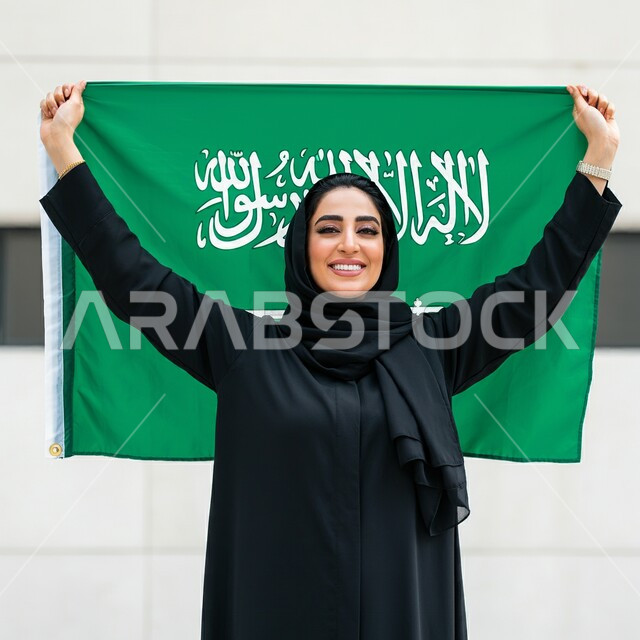 ذكرى العيد الوطني السعودي 23 سبتمبر, بورتريه لامرأة عربية سعودية خليجية محجبة ترتدي العباءة السوداء تحمل بيدها علم السعودية للاحتفال بيوم العلم 11مارس, التعبير عن الفخر والاعتزاز بالانتماء للمملكة