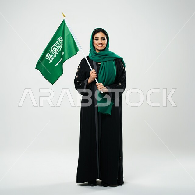 التعبير عن الفخر والاعتزاز بالانتماء للمملكة, ذكرى العيد الوطني السعودي 23 سبتمبر, صورة مقربة لامرأة عربية سعودية خليجية محجبة ترتدي العباءة السوداء تحمل بيدها علم السعودية للاحتفال بيوم العلم 11مارس