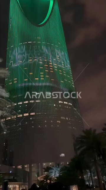 The architectural engineering art of buildings and facilities in the capital, pride in belonging to the national identity, a picture from below of the Kingdom Tower building lit in green in the city of Riyadh, Saudi Arabia at night time, Saudi National Day celebrations on September 23, Saudi Foundation Day activities on February 22