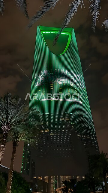 الفن الهندسي المعماري للمباني والمنشآت في العاصمة, الفخر بالانتماء للهوية الوطنية, صورة من الاسفل لمبنى برج المملكة المضاء باللون الأخضر في مدينة الرياض بالسعودية في وقت الليل، احتفالات اليوم الوطني السعودي في 23 سبتمبر، فعاليات يوم التأسيس السعودي 22 فبراير
